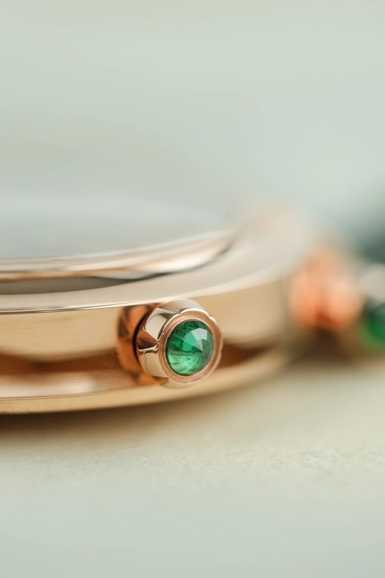 The dial features two rhombus-shaped emeralds on each side of